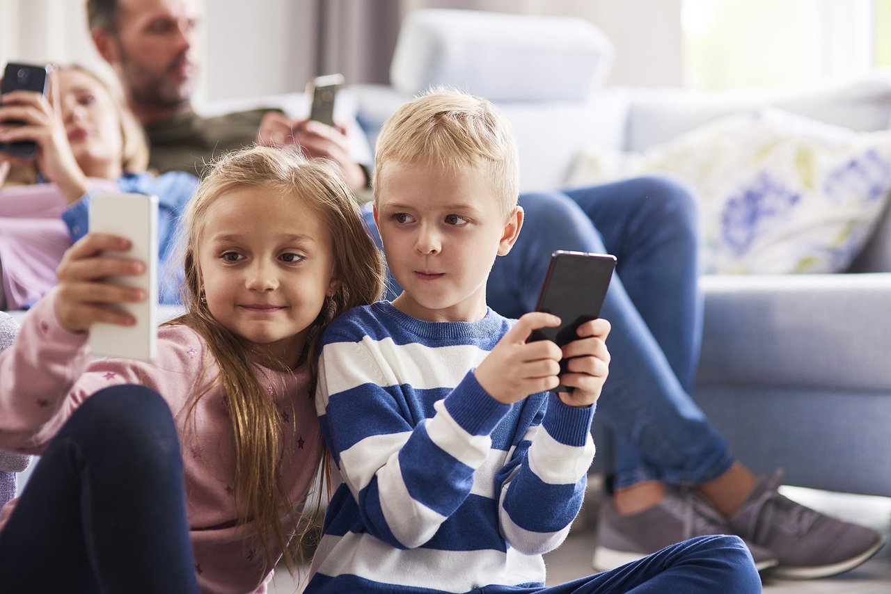 children-using-mobile-phone-living-room